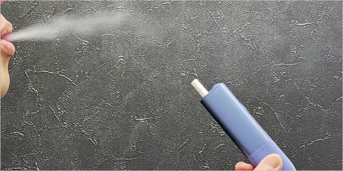 アイコスイルマアイワンで喫煙して煙を吐き出す画像