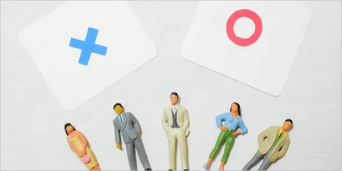 丸とバツが書かれたカードとミニチュアの人々