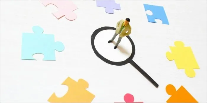 虫眼鏡の上に立つミニチュア男性